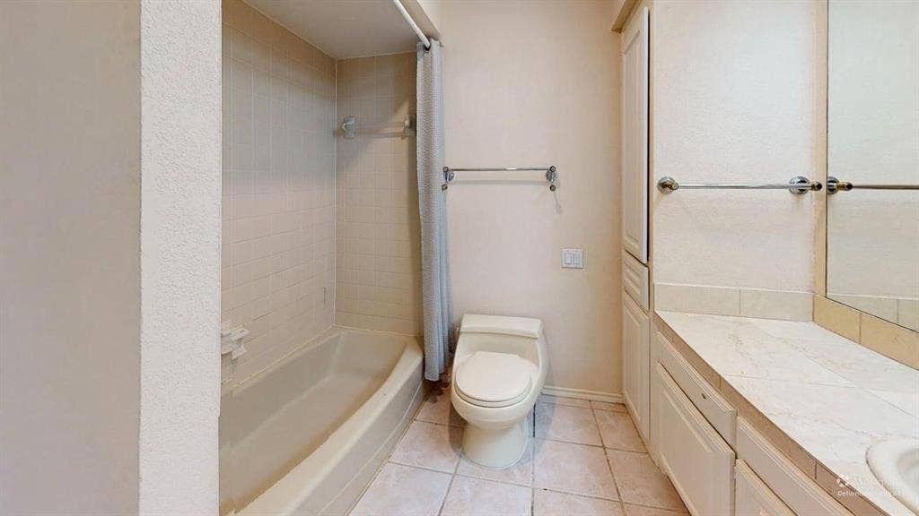 3717 Atrium Drive, Plano, TX 75075 Tiled flooring with a built-in bathtub and shower, complemented by a white vanity with cabinet storage and a mirror