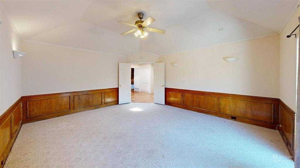 3717 Atrium Drive, Plano, TX 75075 Vaulted ceiling with a ceiling fan, wall-mounted light fixtures, wood-paneled wainscoting, and carpeted flooring