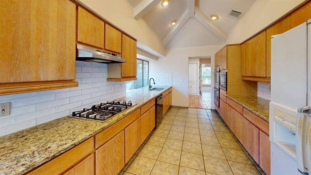 3717 Atrium Drive, Plano, TX 75075 Kitchen featuring vaulted ceilings with exposed beams, recessed lighting, wood cabinetry, granite countertops, and tile flooring