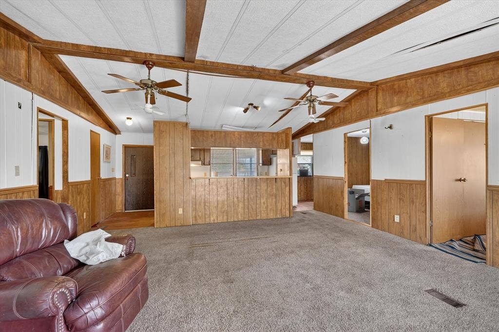 11929 County Road 950, Rockwall, TX 75087 Vaulted ceiling with exposed wood beams, ceiling fans, wood-finish wall paneling, and wall-to-wall carpeting