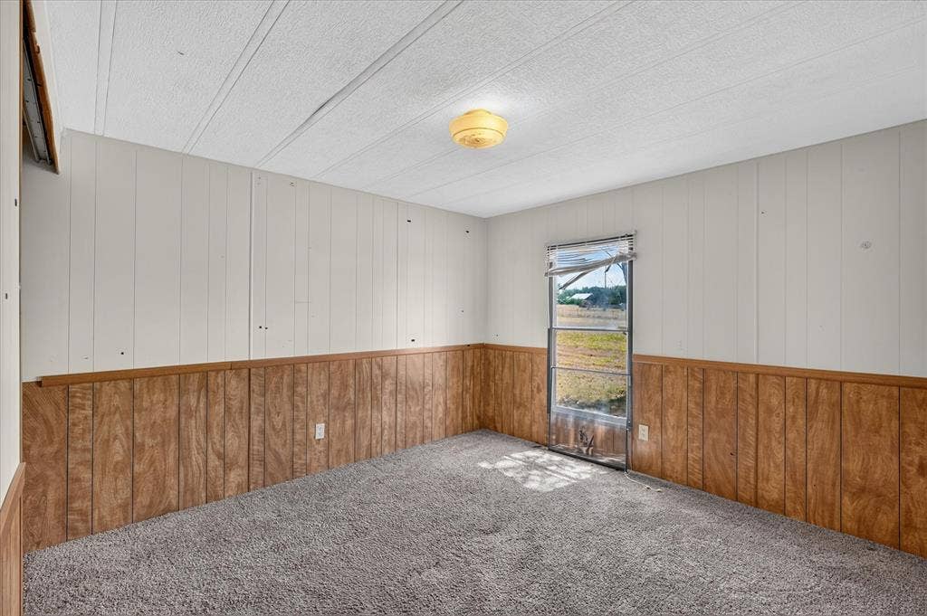 11929 County Road 950, Rockwall, TX 75087 Textured wall-to-wall carpeting, wood-finish paneling, white vertical plank walls, and a flush-mount ceiling light