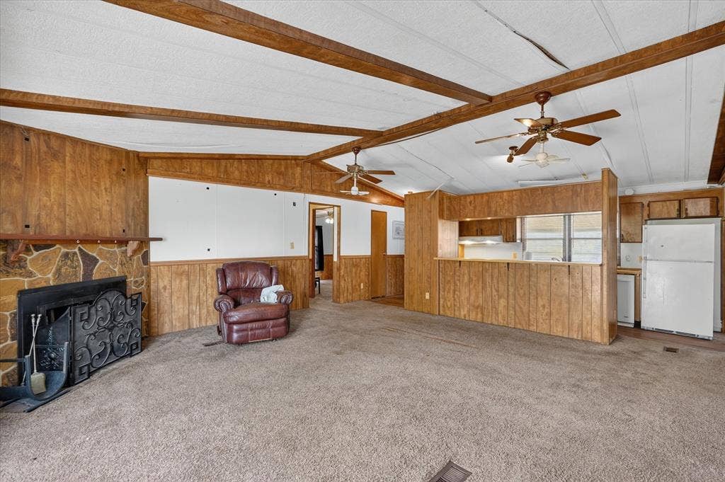 11929 County Road 950, Rockwall, TX 75087 Exposed ceiling beams, two ceiling fans, stone-finish fireplace, wood-finish wall panels, and a kitchen pass-through window