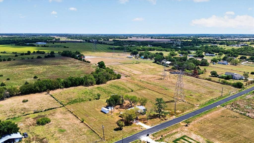 11929 County Road 950, Rockwall, TX 75087 Expansive rural landscape featuring a paved road, scattered structures, and mature trees
