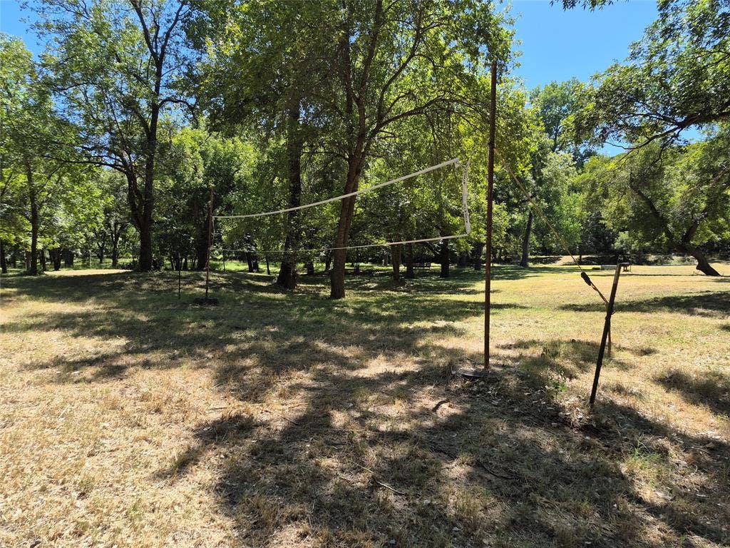 8324 River Court, Granbury, TX 76048 Expansive outdoor area with mature trees and a dedicated recreational net