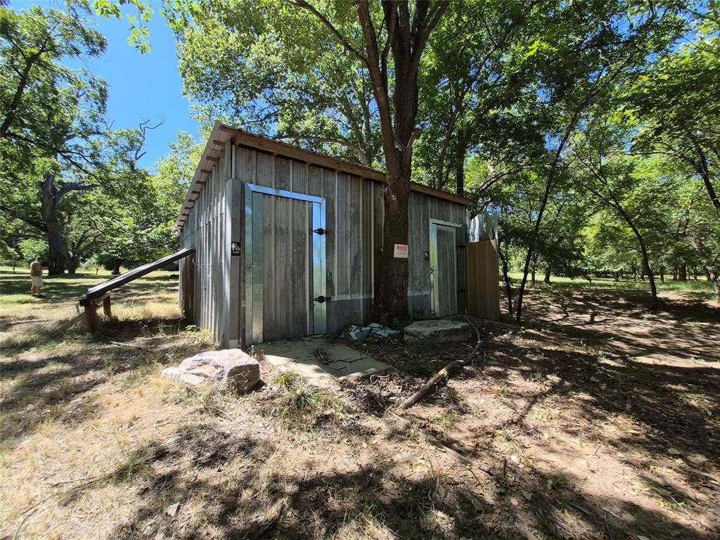 8324 River Court, Granbury, TX 76048 Wood-sided outbuilding with two entrance doors, surrounded by mature trees