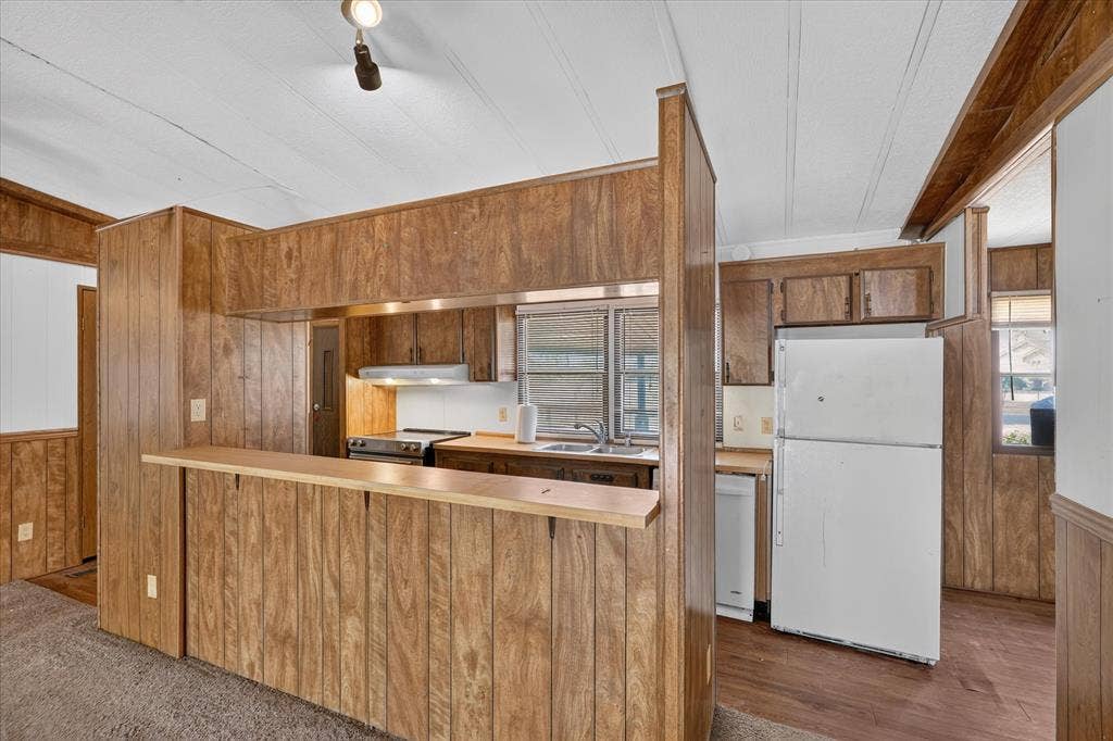 11929-1 County Road 950, Rockwall, TX 75087 Kitchen featuring wood-panel walls, wood-finish flooring, wood cabinetry, built-in stainless steel oven, and a double-basin stainless steel sink