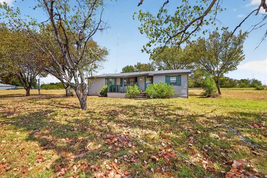 11929-1 County Road 950, Rockwall, TX 75087 Single-story residence with light-colored siding, green shutters, and a covered porch entry