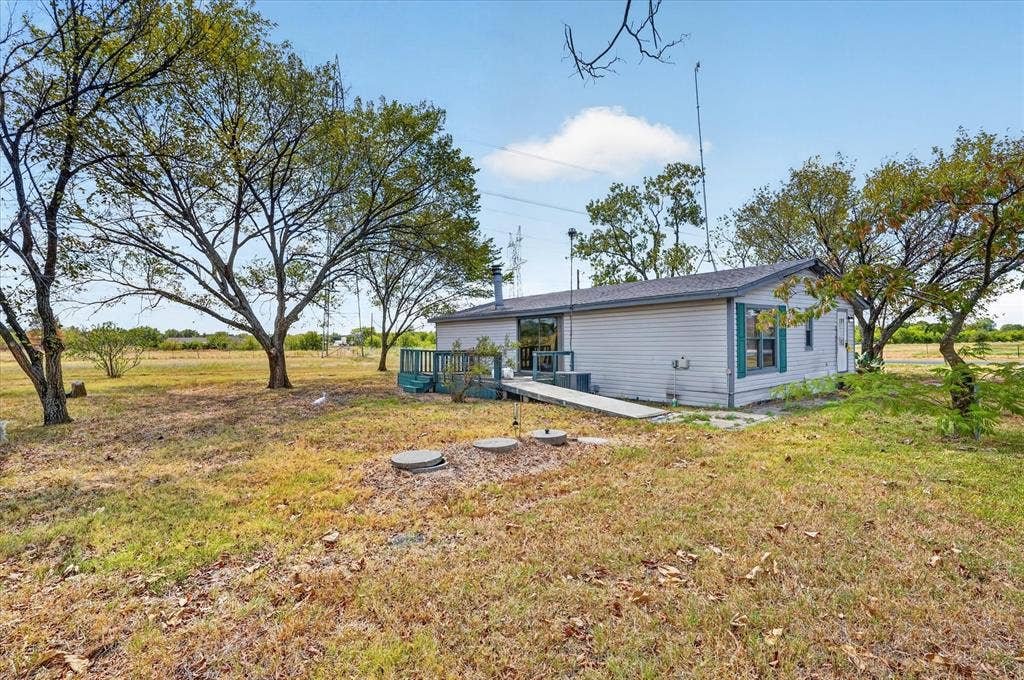 11929-1 County Road 950, Rockwall, TX 75087 Single-story residence with light-colored siding, a dark shingle roof, and green window shutters