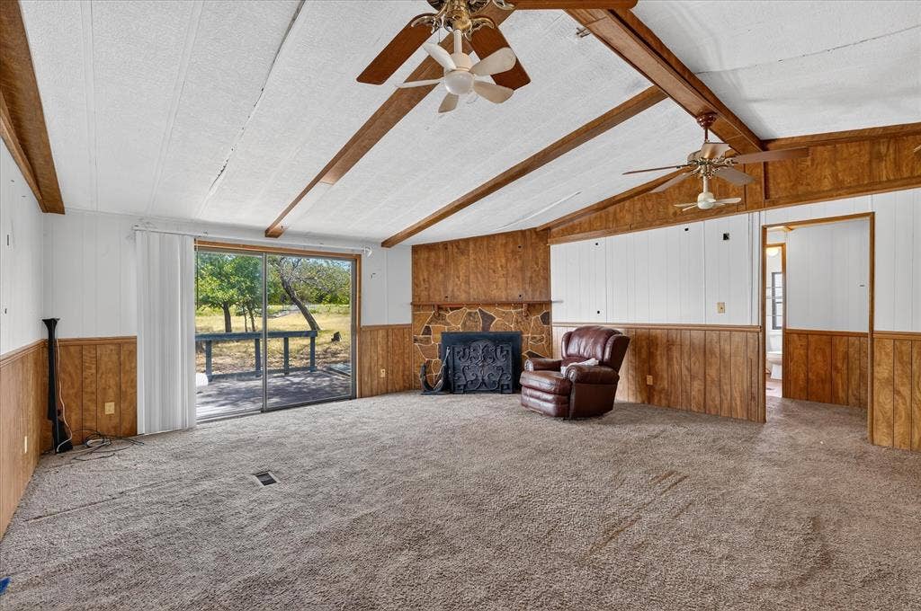 11929-1 County Road 950, Rockwall, TX 75087 Vaulted ceiling with exposed wood beams, stone-faced fireplace, ceiling fans, and sliding glass door