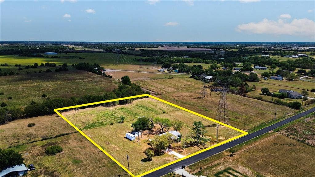 11929-1 County Road 950, Rockwall, TX 75087 Expansive rural property featuring a primary structure, mature trees, and an accessory building, bordered by a paved road
