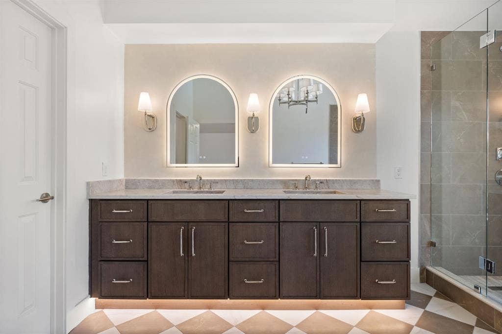 7504 Hughes Drive, Plano, TX 75024 Double vanity with dark wood-finish cabinetry, light stone countertop, and two vessel sinks