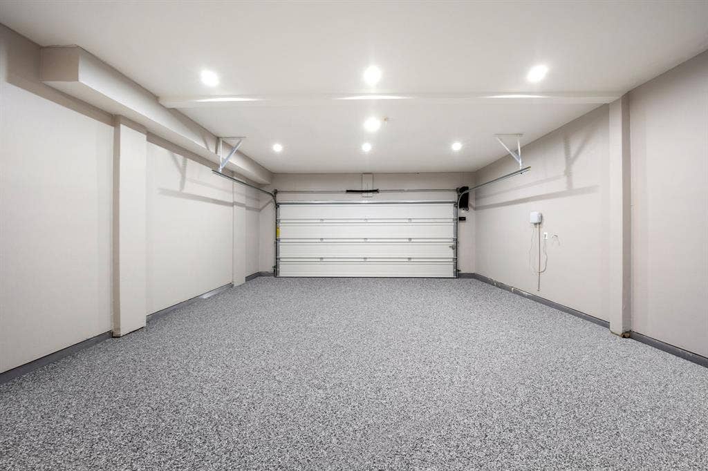 7504 Hughes Drive, Plano, TX 75024 Spacious garage featuring a speckled epoxy floor, recessed ceiling lighting, a panel garage door, and light neutral wall tones