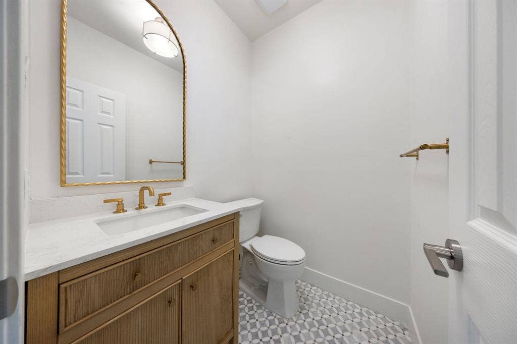 7504 Hughes Drive, Plano, TX 75024 Powder room featuring a wood-finish vanity with a white countertop and integrated rectangular sink