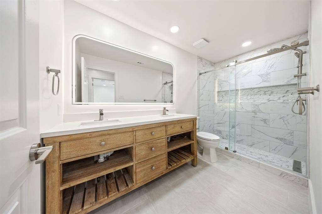 7504 Hughes Drive, Plano, TX 75024 Double vanity with wood-finish cabinetry, white countertop, and dual undermount sinks