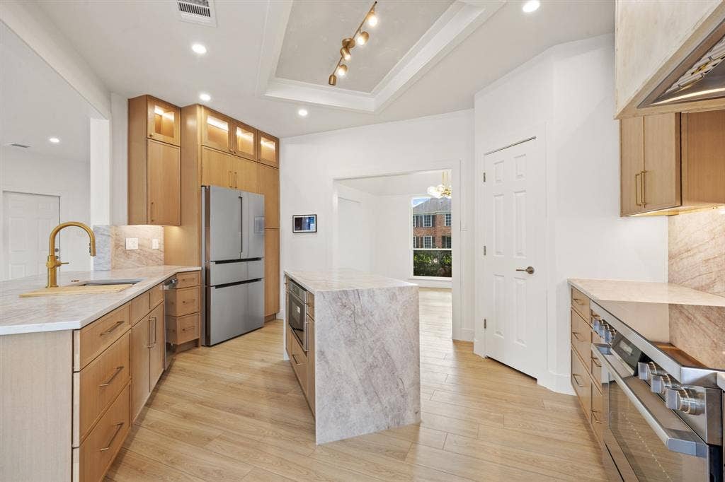 7504 Hughes Drive, Plano, TX 75024 Modern kitchen featuring light wood-finish cabinetry, stainless steel appliances, and light-toned countertops
