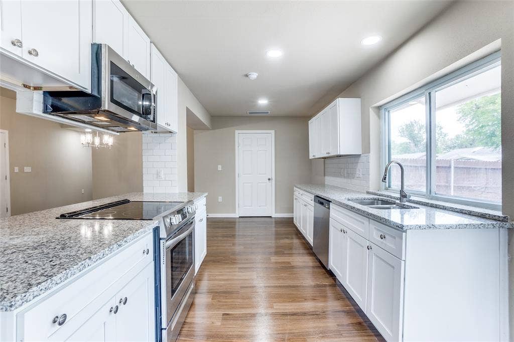 1904 Richland Drive, Richardson, TX 75081 Kitchen featuring white shaker-style cabinetry, stainless steel appliances, granite countertops, and wood-finish flooring