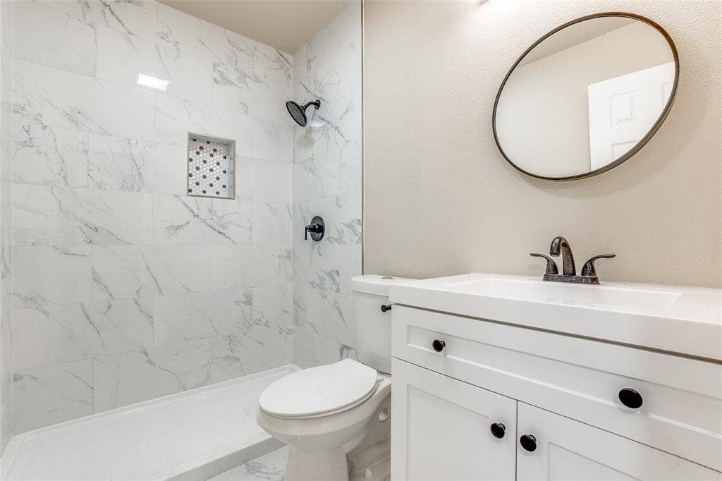 1904 Richland Drive, Richardson, TX 75081 White vanity with integrated sink, black hardware, and an oval mirror