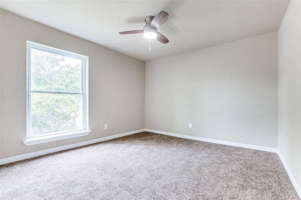 1904 Richland Drive, Richardson, TX 75081 Neutral tone wall paint, light gray carpeting, ceiling fan with integrated lighting, and a double-hung window