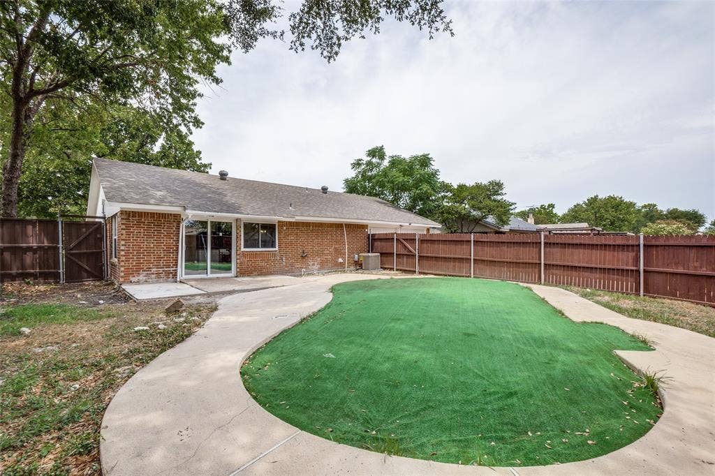 1904 Richland Drive, Richardson, TX 75081 Brick exterior, sliding glass door, paved patio, perimeter fencing, synthetic turf area