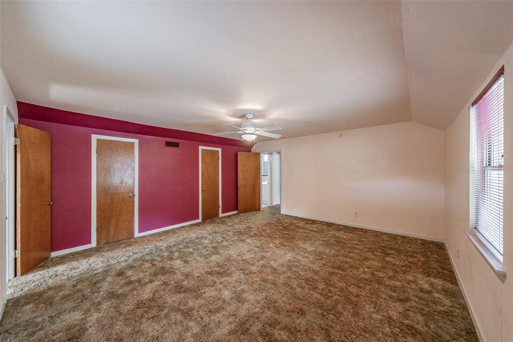 1313 Killian Drive, Arlington, TX 76013 Spacious room featuring sloped ceilings, multiple wood-panel doors, a ceiling fan, and a window with blinds