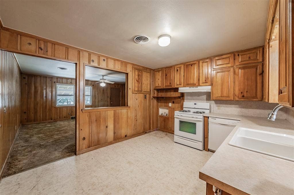1313 Killian Drive, Arlington, TX 76013 Kitchen featuring wood cabinetry, white gas range, white dishwasher, and a pass-through opening to an adjacent room