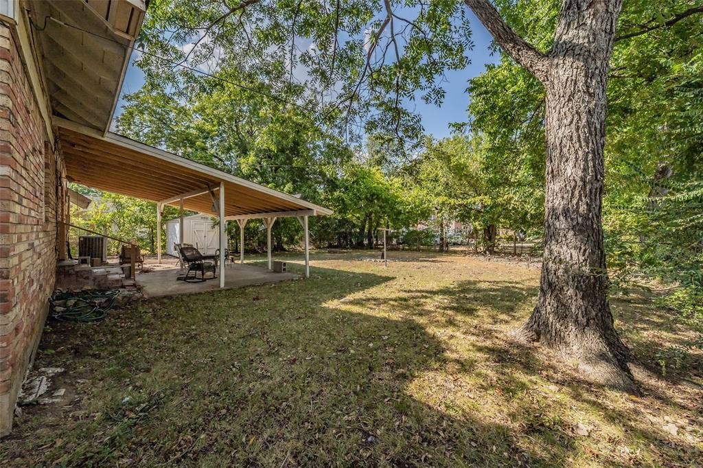 1313 Killian Drive, Arlington, TX 76013 Expansive backyard featuring a covered patio with concrete flooring, mature trees, and a brick exterior