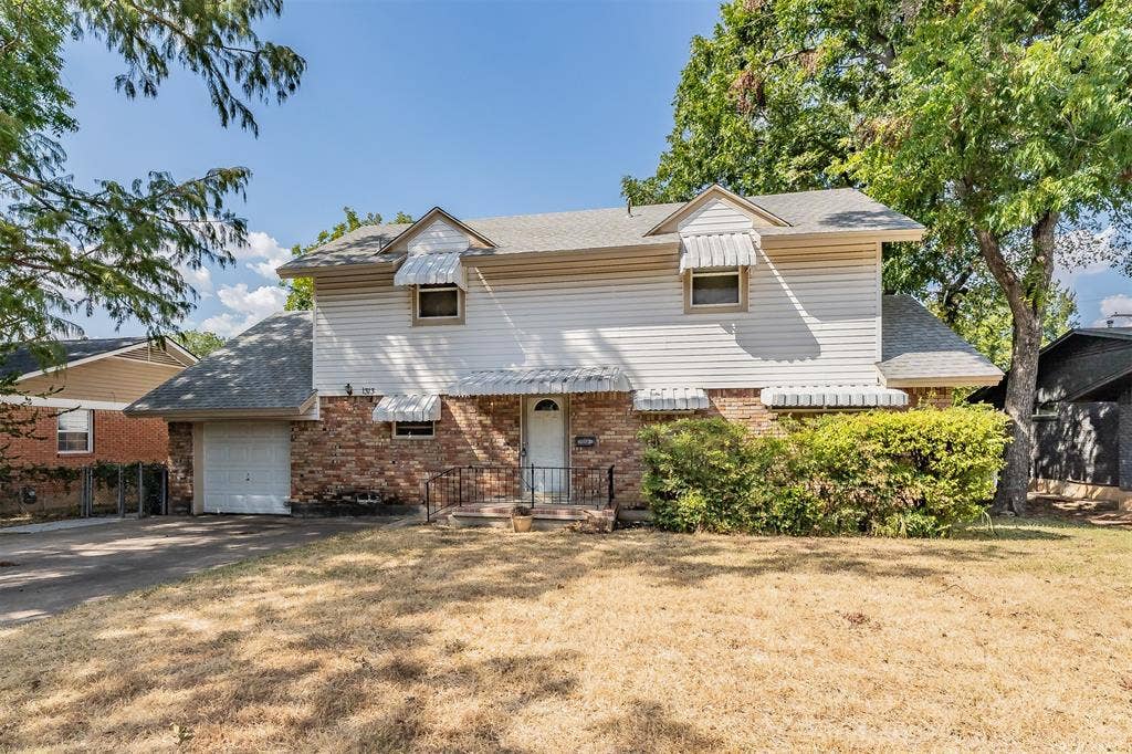 1313 Killian Drive, Arlington, TX 76013 Two-story residence featuring brick and siding exterior, front entry with wrought iron railing, single-car garage, and established landscaping