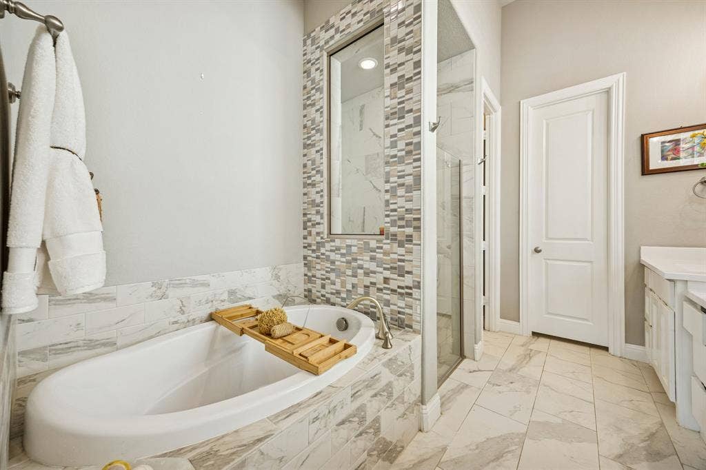 garden tub and separate shower with view of door leading to huge walk-in closet