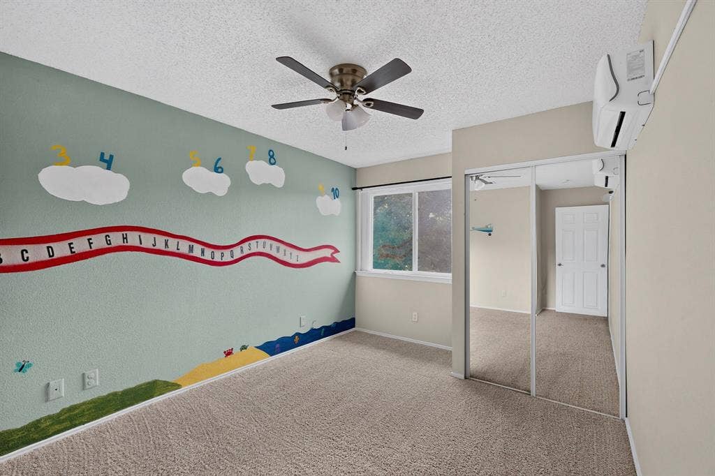 6747 Silver Sage Drive, Fort Worth, TX 76137 Wall-mounted air conditioning unit, ceiling fan, mirrored closet doors, and carpeted flooring
