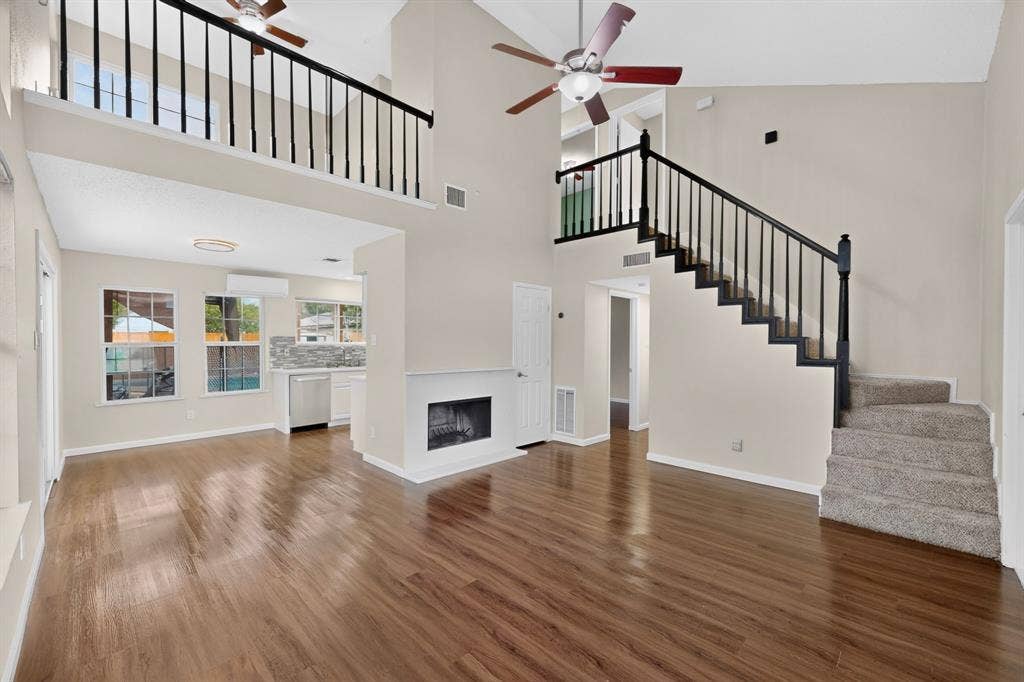 6747 Silver Sage Drive, Fort Worth, TX 76137 Open-concept living space featuring wood-finish flooring, a fireplace, and a carpeted staircase with a dark wood banister