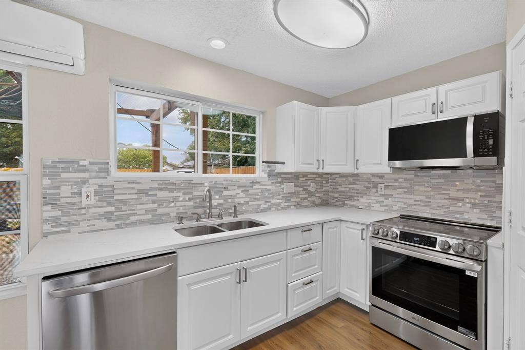 6747 Silver Sage Drive, Fort Worth, TX 76137 White cabinetry with stainless steel appliances, solid surface countertops, and a full tile backsplash