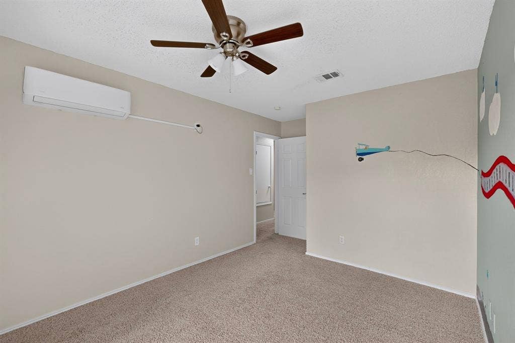 6747 Silver Sage Drive, Fort Worth, TX 76137 Carpeted flooring with a ceiling fan, a wall-mounted air conditioning unit, and a white interior door