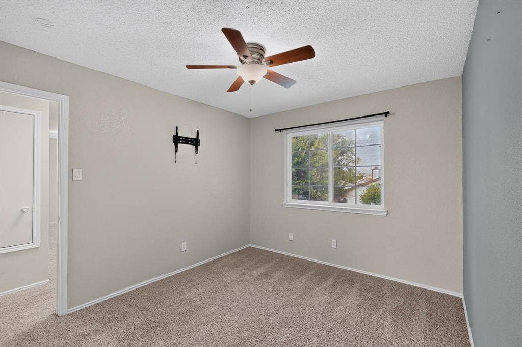 6747 Silver Sage Drive, Fort Worth, TX 76137 Textured carpet flooring, window with exterior landscape, ceiling fan with light fixture, neutral wall paint, and white trim