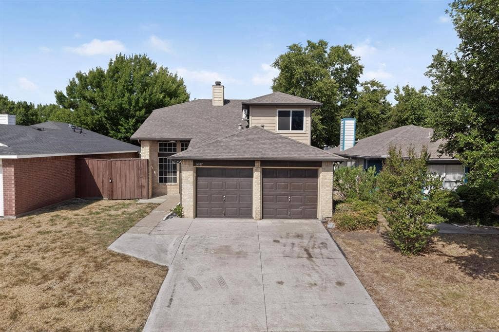 6747 Silver Sage Drive, Fort Worth, TX 76137 Brick and siding exterior with a two-car garage, multiple windows, and mature trees surrounding the property