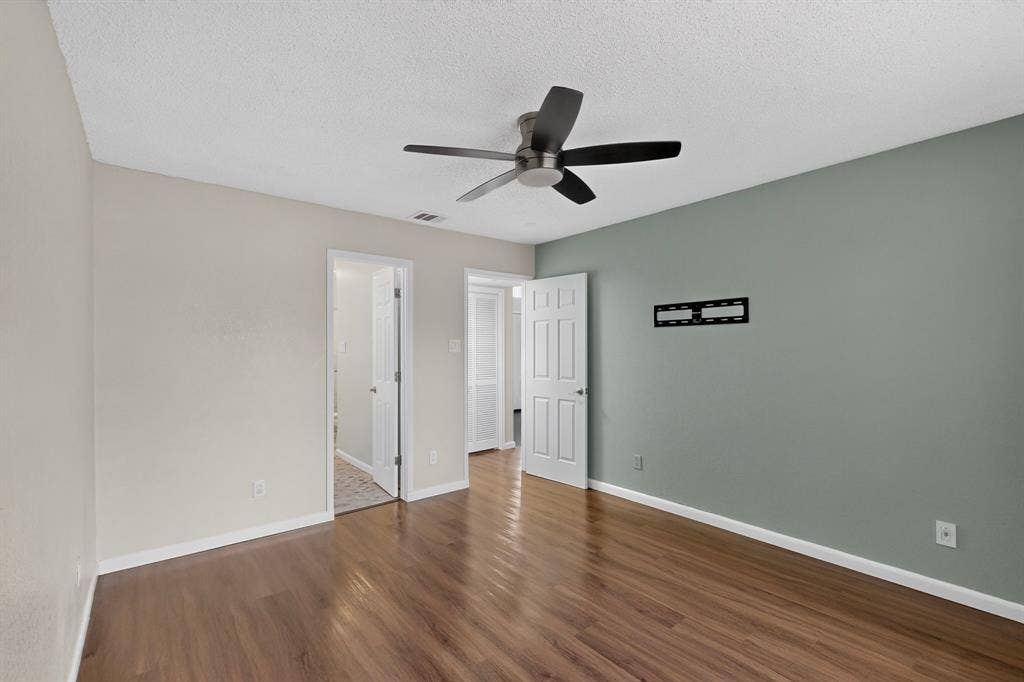 6747 Silver Sage Drive, Fort Worth, TX 76137 Wood-finish flooring, ceiling fan with matte black blades, white interior doors, and a wall-mounted bracket