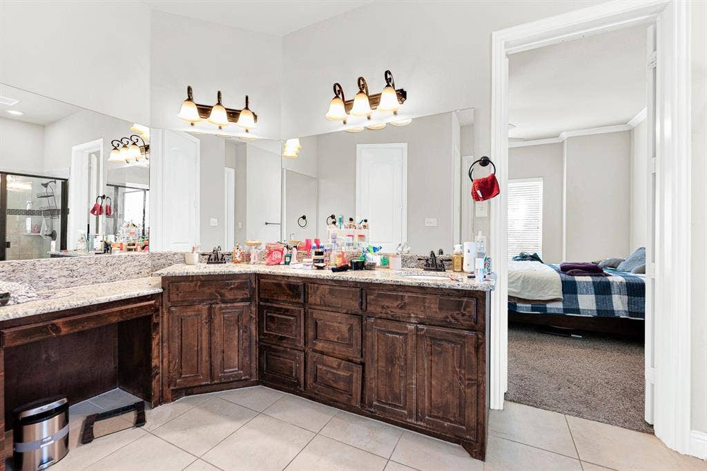 12038 Big Springs Drive, Frisco, TX 75035 An expansive L-shaped vanity setup topped with granite offers dual sinks and an integrated vanity seating area under bright, warm lighting. You will love having your own space to comfortably prep and unwind during busy morning routines.