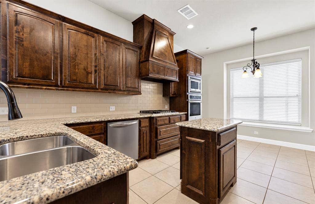 12038 Big Springs Drive, Frisco, TX 75035 Photo digitally enhanced using AI. Rich, dark wood cabinets extend almost to the ceiling, grounding the light-filled cooking space. Visualize yourself baking morning treats on the granite counters as soft light streams through the nearby window.