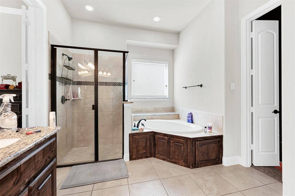 12038 Big Springs Drive, Frisco, TX 75035 A dedicated glass-enclosed shower stands alongside a deep corner soaking tub tucked neatly beneath a bright frosted window. End your day here with a peaceful, spa-like soak to wash the afternoon away.