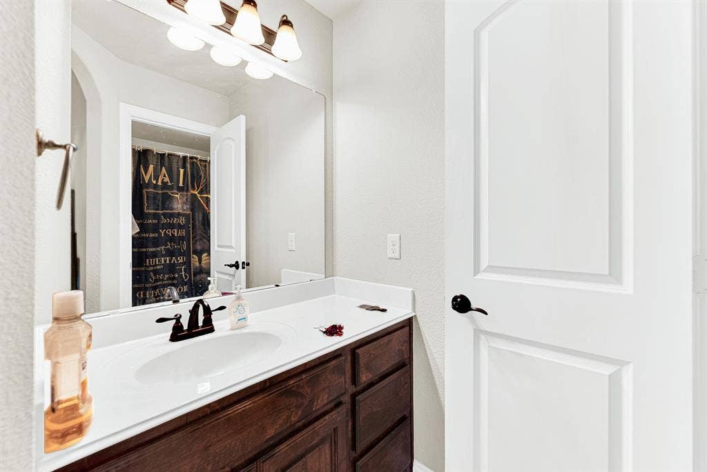 12038 Big Springs Drive, Frisco, TX 75035 A wide mirror stretches over rich wood cabinetry to reflect light across the vanity area. It provides a comfortable, hassle-free spot for kids or guests to get ready in the morning.
