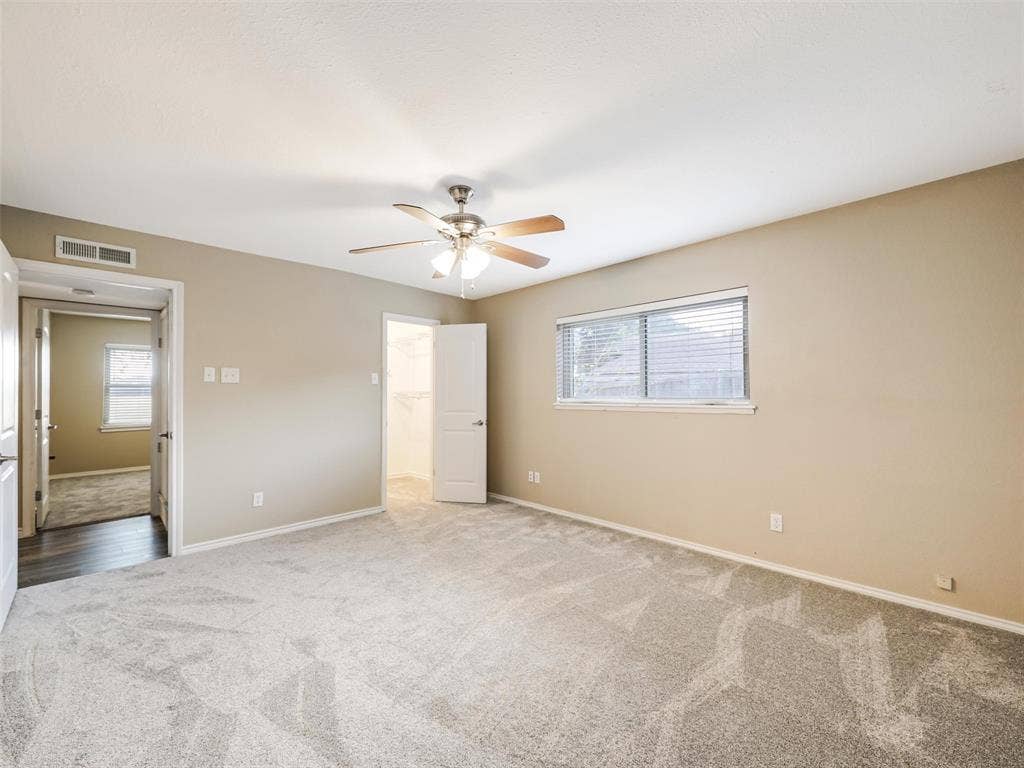Recessed window with horizontal blinds, ceiling fan with integrated lighting, neutral wall paint, and gray patterned carpeting