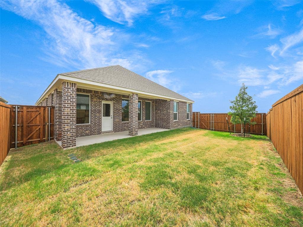 2517 Greenbelt Road, Celina, TX 75009 Rear elevation with a covered patio, brick columns, and a fully fenced yard