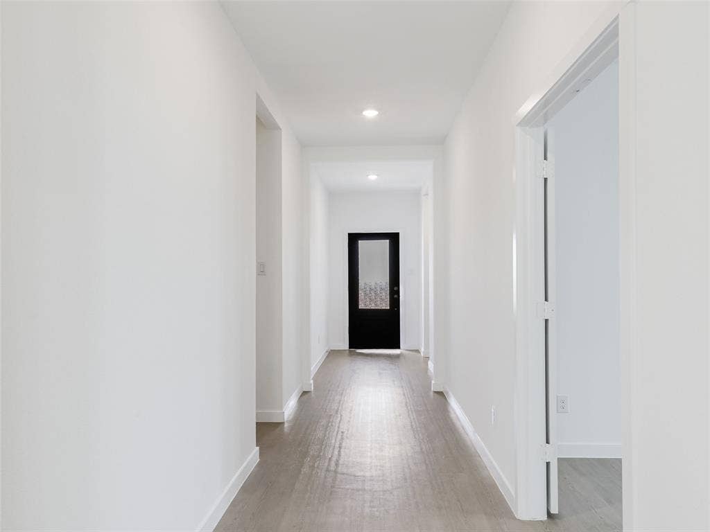 2517 Greenbelt Road, Celina, TX 75009 Recessed lighting illuminates the hallway, featuring light wood-finish flooring and a black door with frosted glass