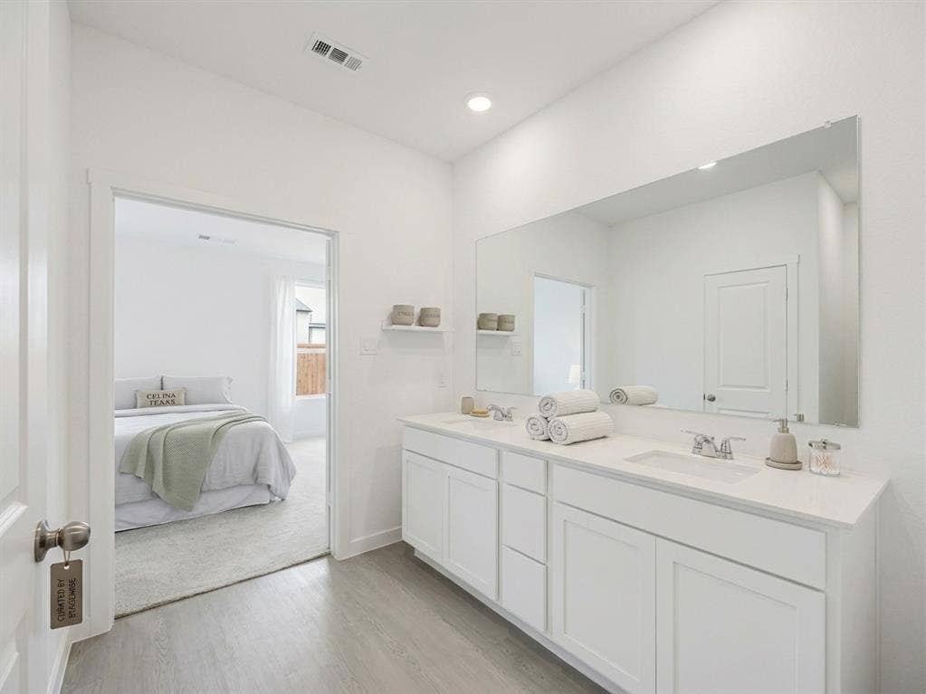 2517 Greenbelt Road, Celina, TX 75009 Dual vanity with undermount sinks, white cabinetry, and a full-width mirror