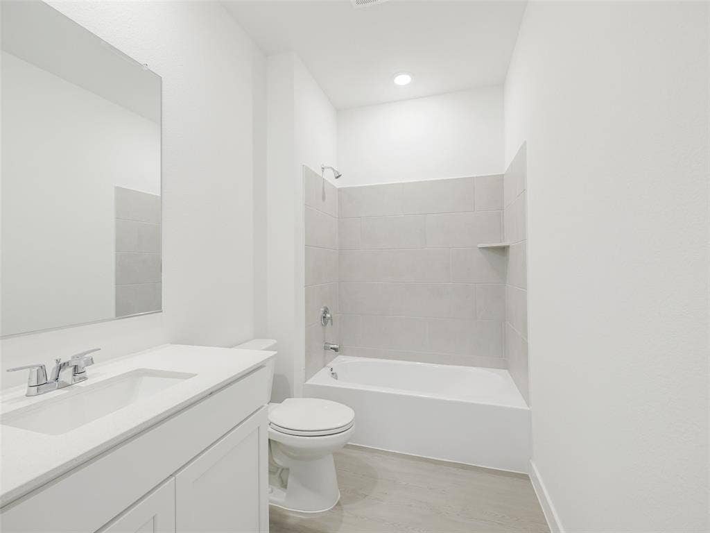 2517 Greenbelt Road, Celina, TX 75009 White vanity with integrated sink, rectangular mirror, chrome faucet, white bathtub with light-colored tile surround, recessed lighting