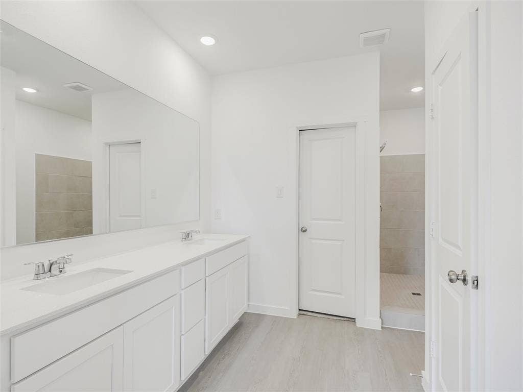 2517 Greenbelt Road, Celina, TX 75009 Dual vanity with white cabinetry, integrated sinks, chrome fixtures, and a spacious wall-mounted mirror