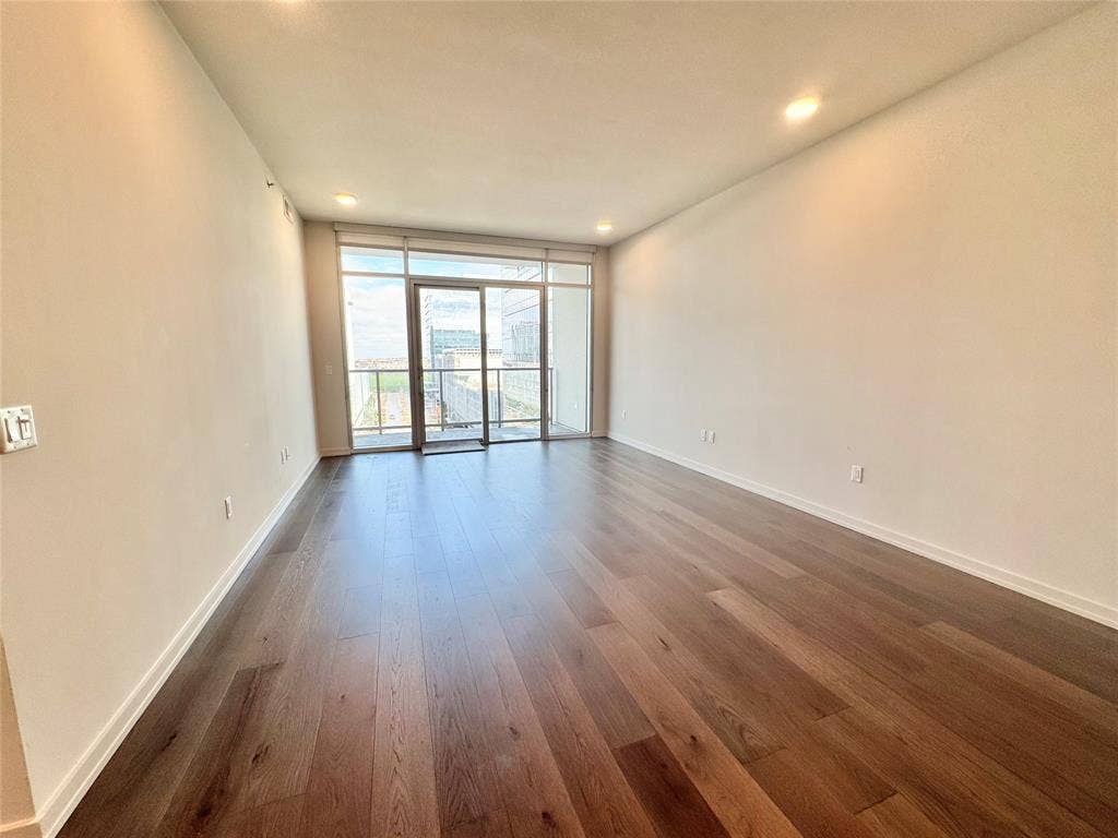 6911 Cowboys Way, #803, Frisco, TX 75034 Empty room featuring expansive windows and dark hardwood / wood-style flooring