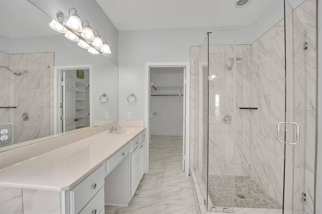 Dual-sink vanity with light-toned countertop, extensive mirror, and built-in cabinetry