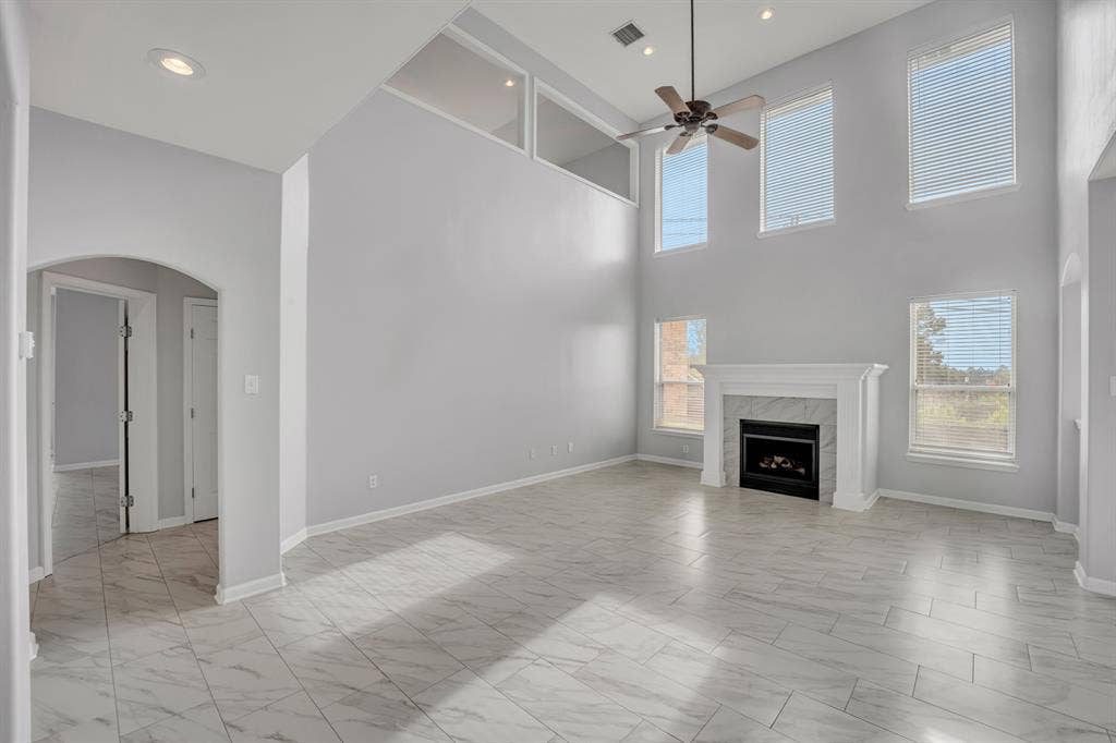 Vaulted ceilings, a built-in fireplace with a stone surround, and multiple windows with blinds