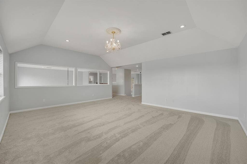 Vaulted ceiling, recessed lighting, chandelier, neutral carpeting, and interior transom windows