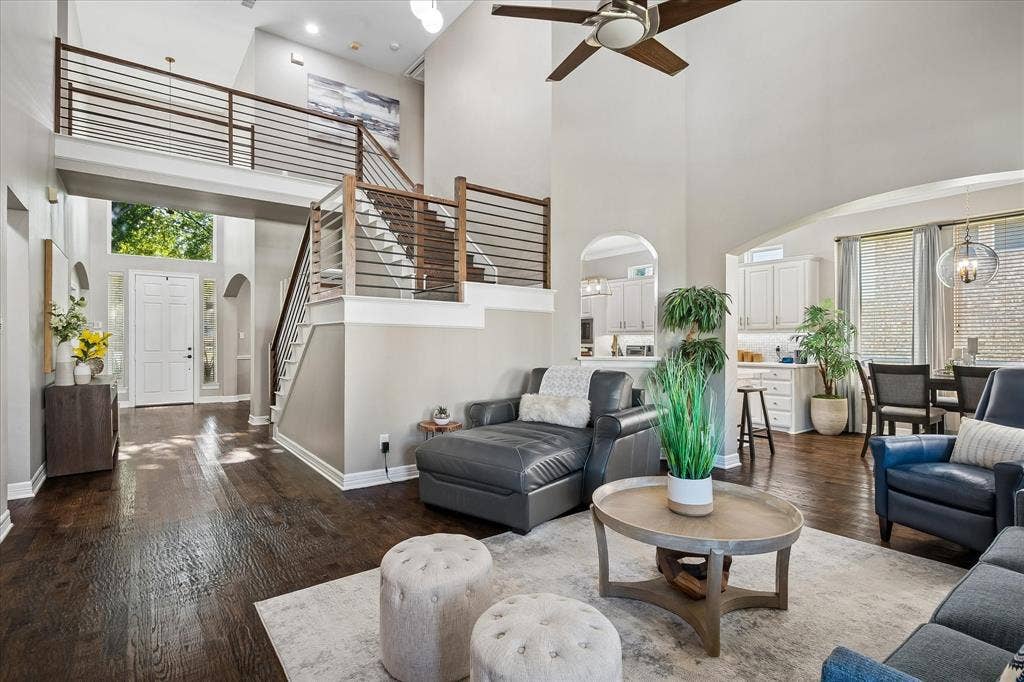 7525 Cedar Elm Drive, Irving, TX 75063 Two-story living area with high ceilings, wood-finish flooring, and a contemporary open-riser staircase with horizontal metal railings